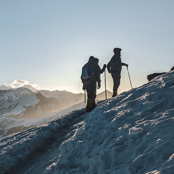 Two people climbing a snowy hill