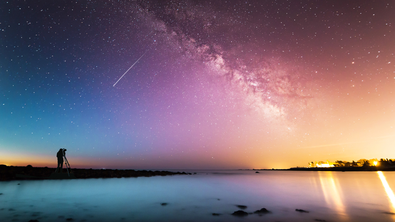 Person looking at shooting star in colourful starry sky