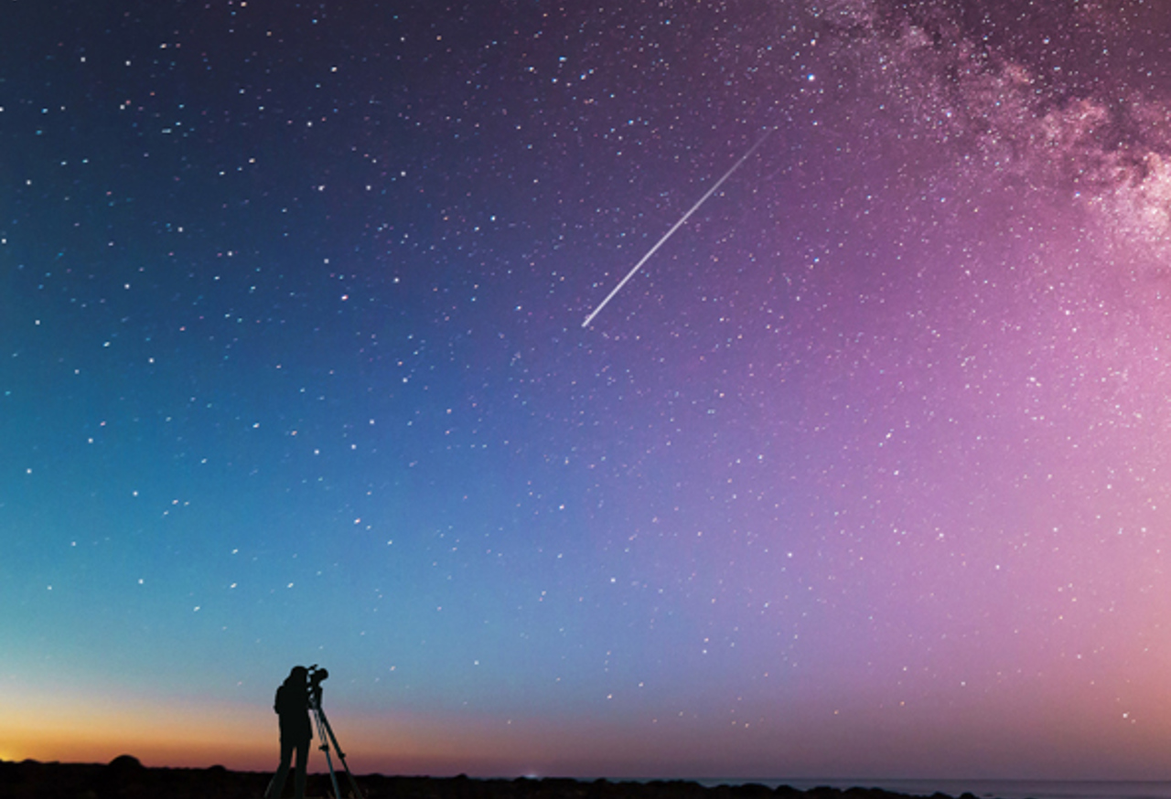 Person looking at shooting star in starry sky