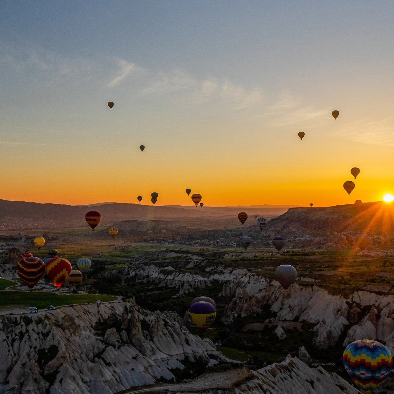 Hot air balloons floating over valleys during sunset
